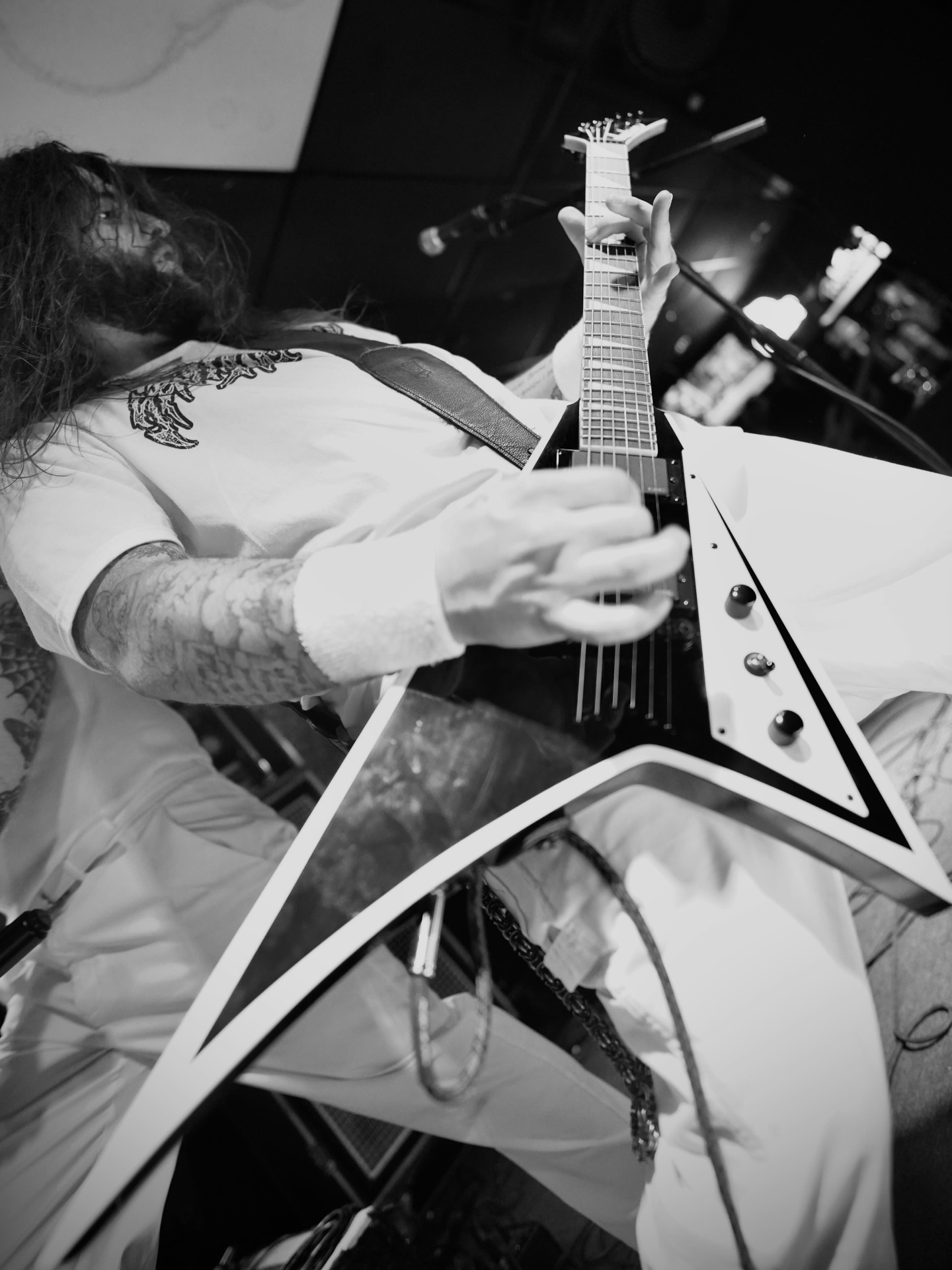 Guitarist playing white Flying V from below in black and white