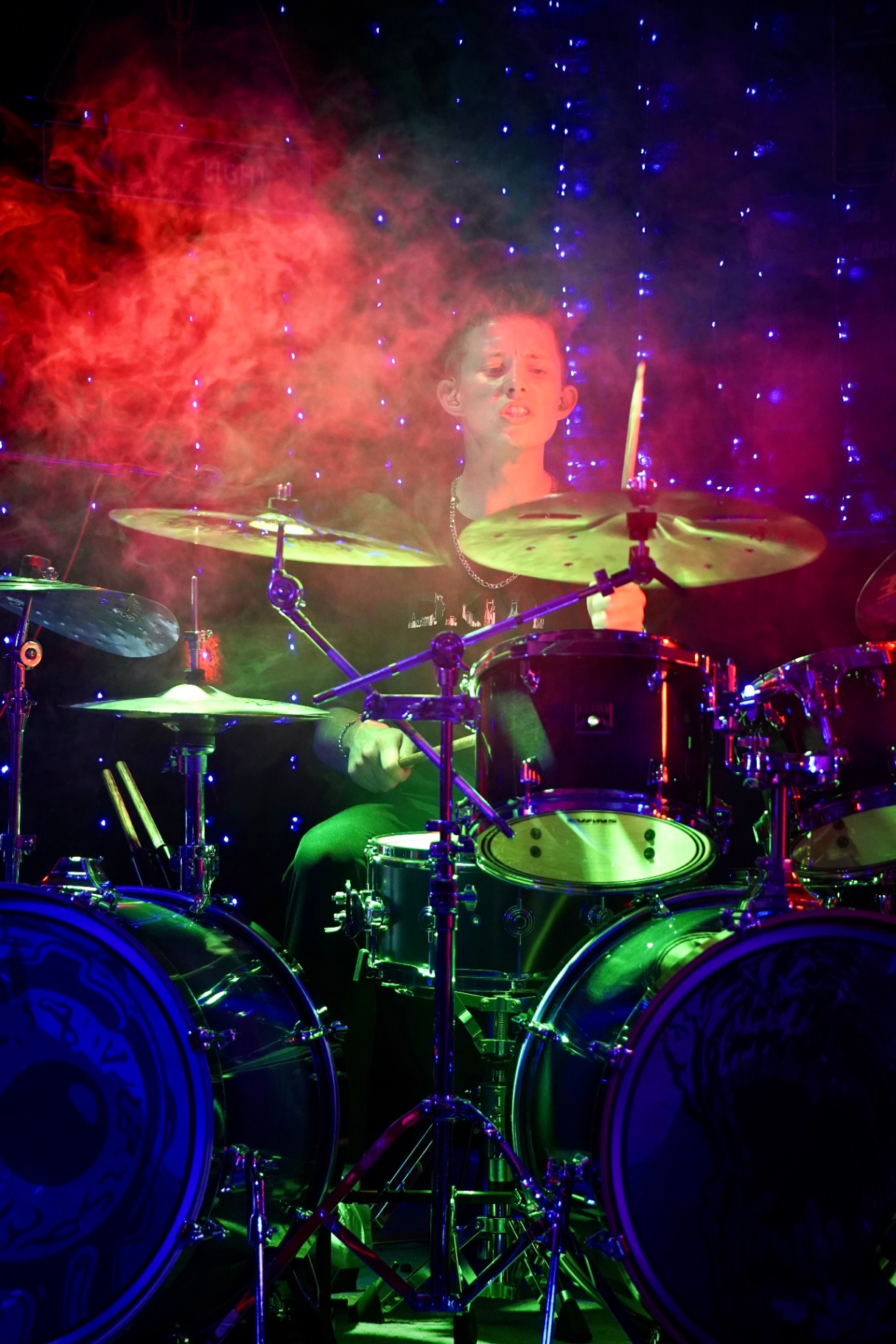 Drummer surrounded by red and blue smoke behind the kit
