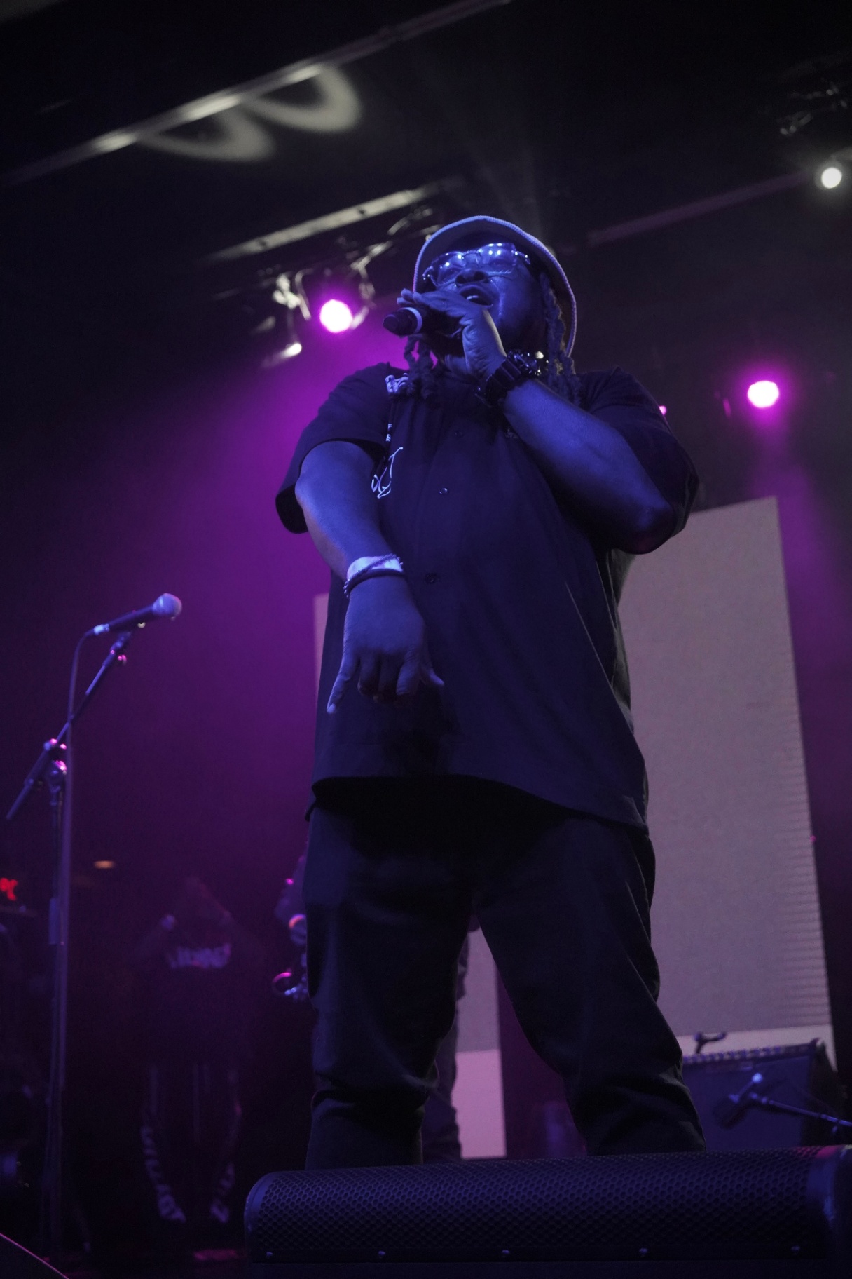 MC in bucket hat commanding the stage under purple light