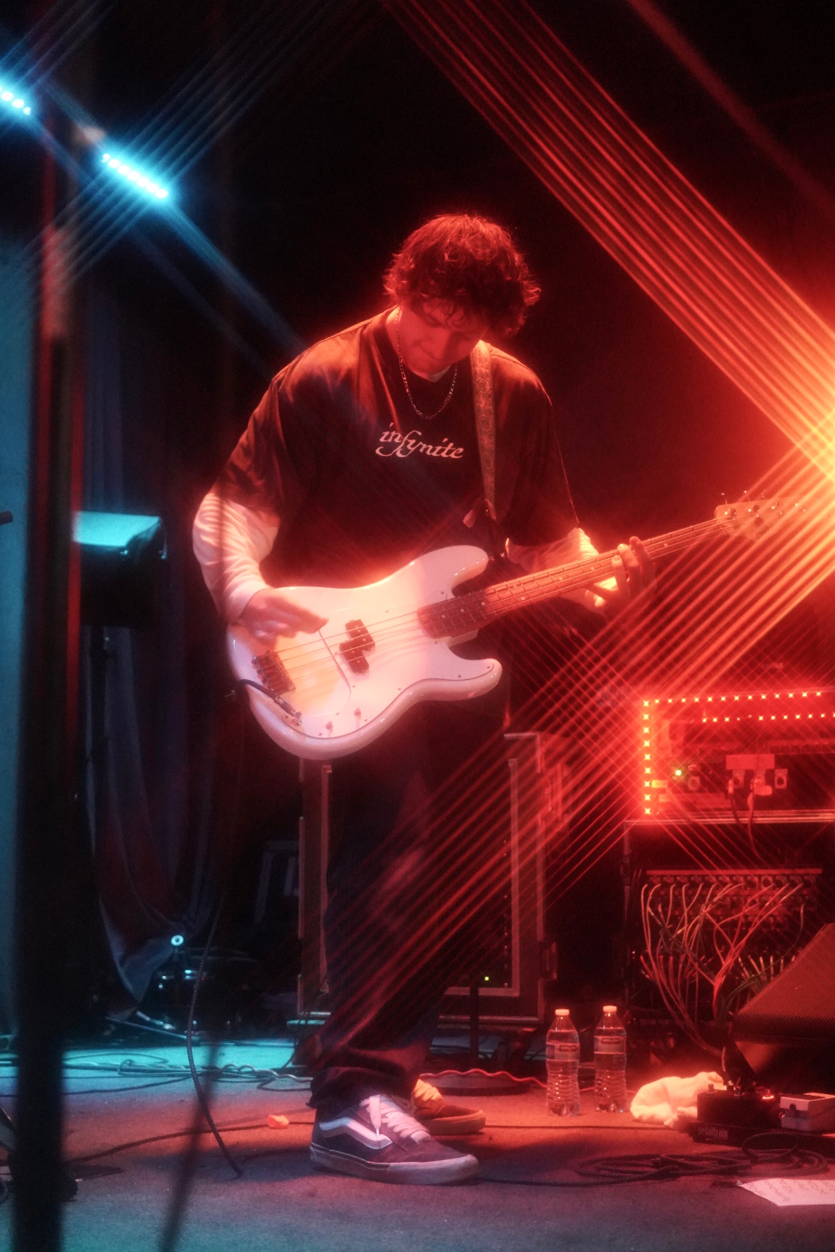 Bassist with white P-bass cut by red laser lines on stage