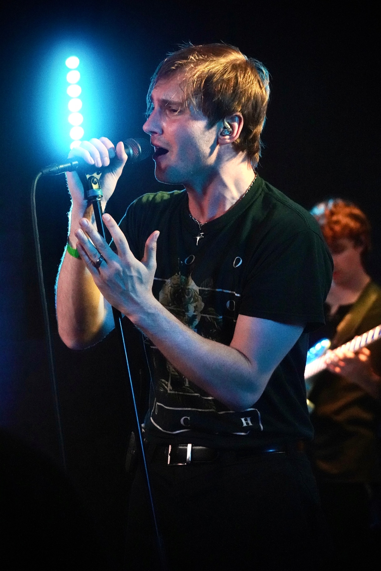 Vocalist singing into a mic on a stand under blue stage light