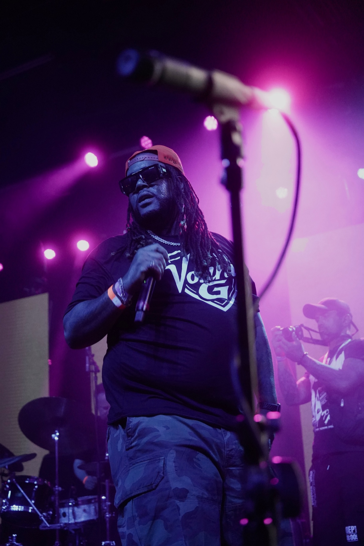 Vonni G on stage in magenta light with hanging mic overhead