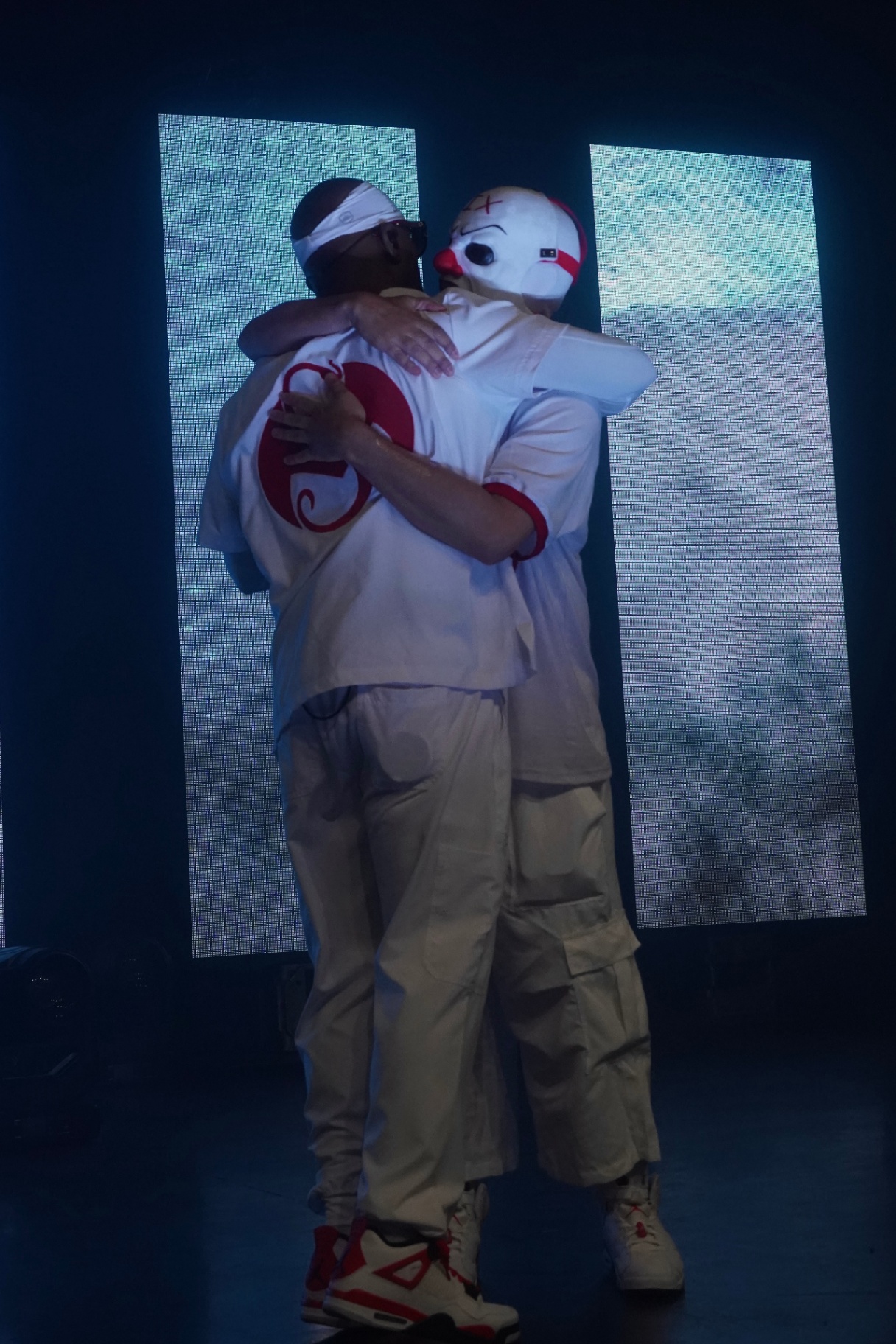 Tech N9ne and Krizz Kaliko hugging on stage against LED panels