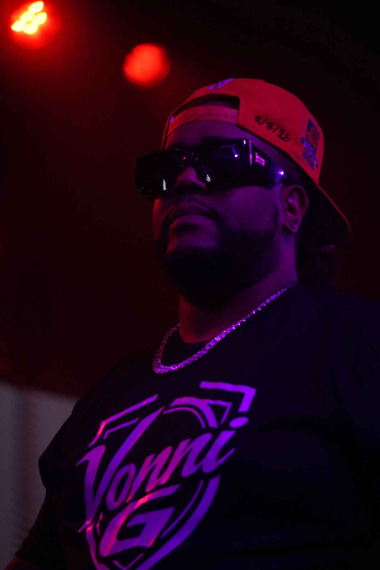 Vonni G in red cap and shades under red and purple light