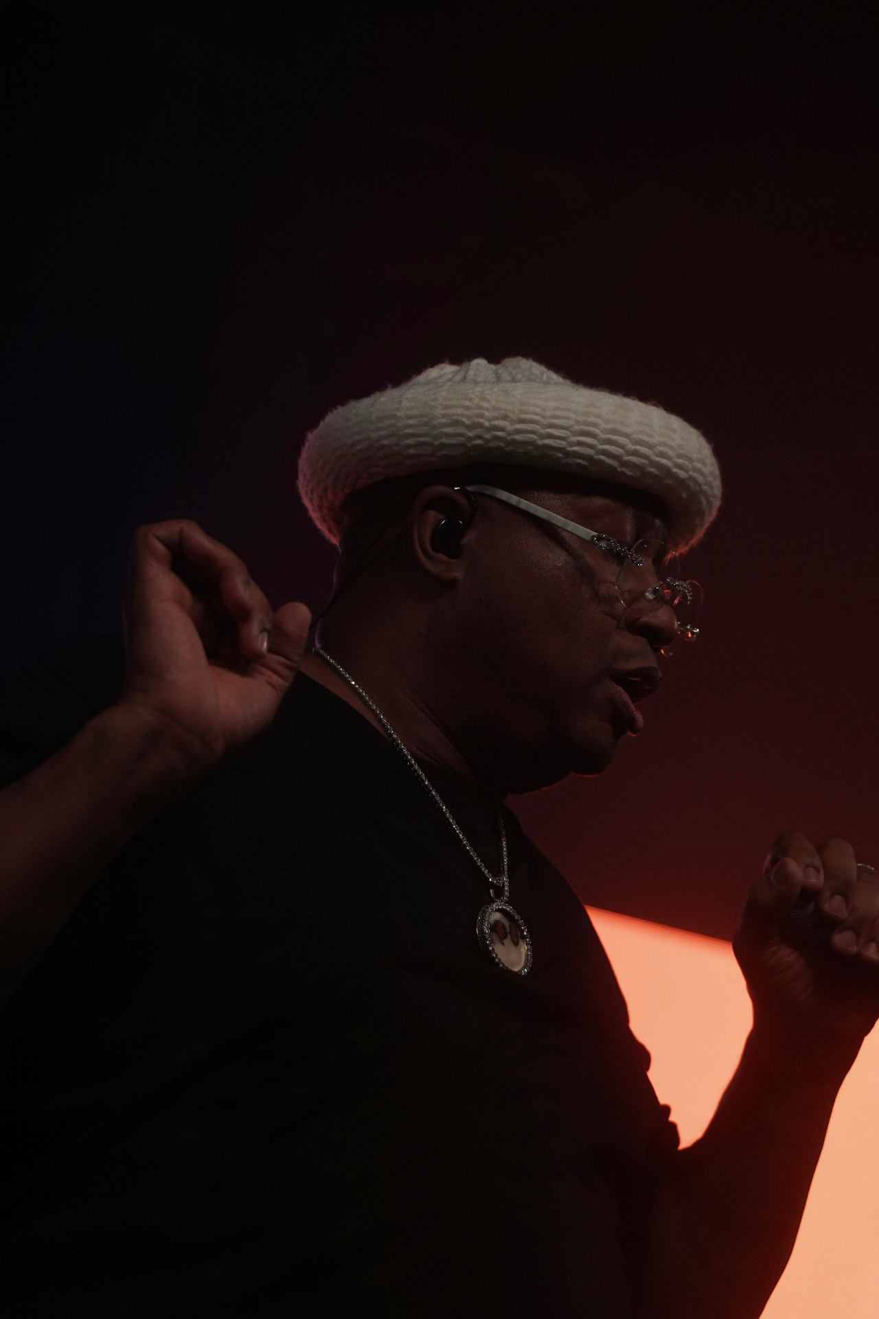E-40 in profile with white bucket hat glowing against orange backlight