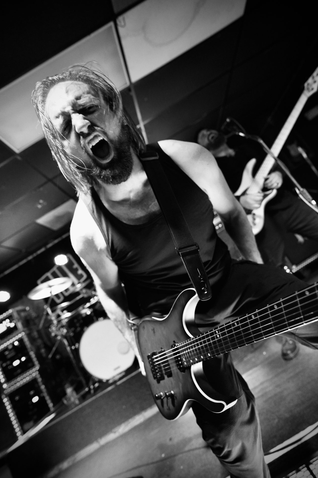 Guitarist screaming mid-performance in black and white