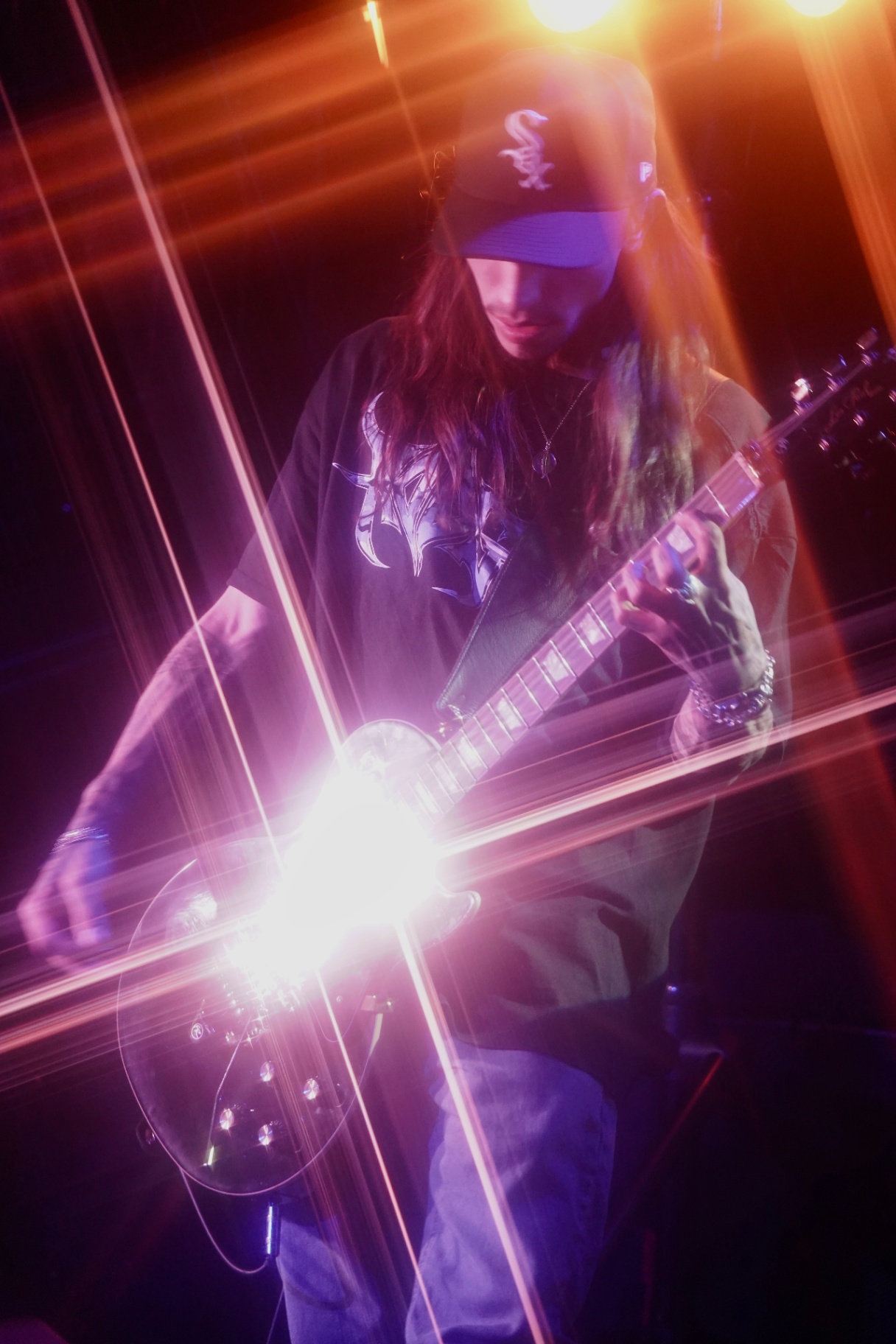 Long-haired guitarist under intense orange light flare