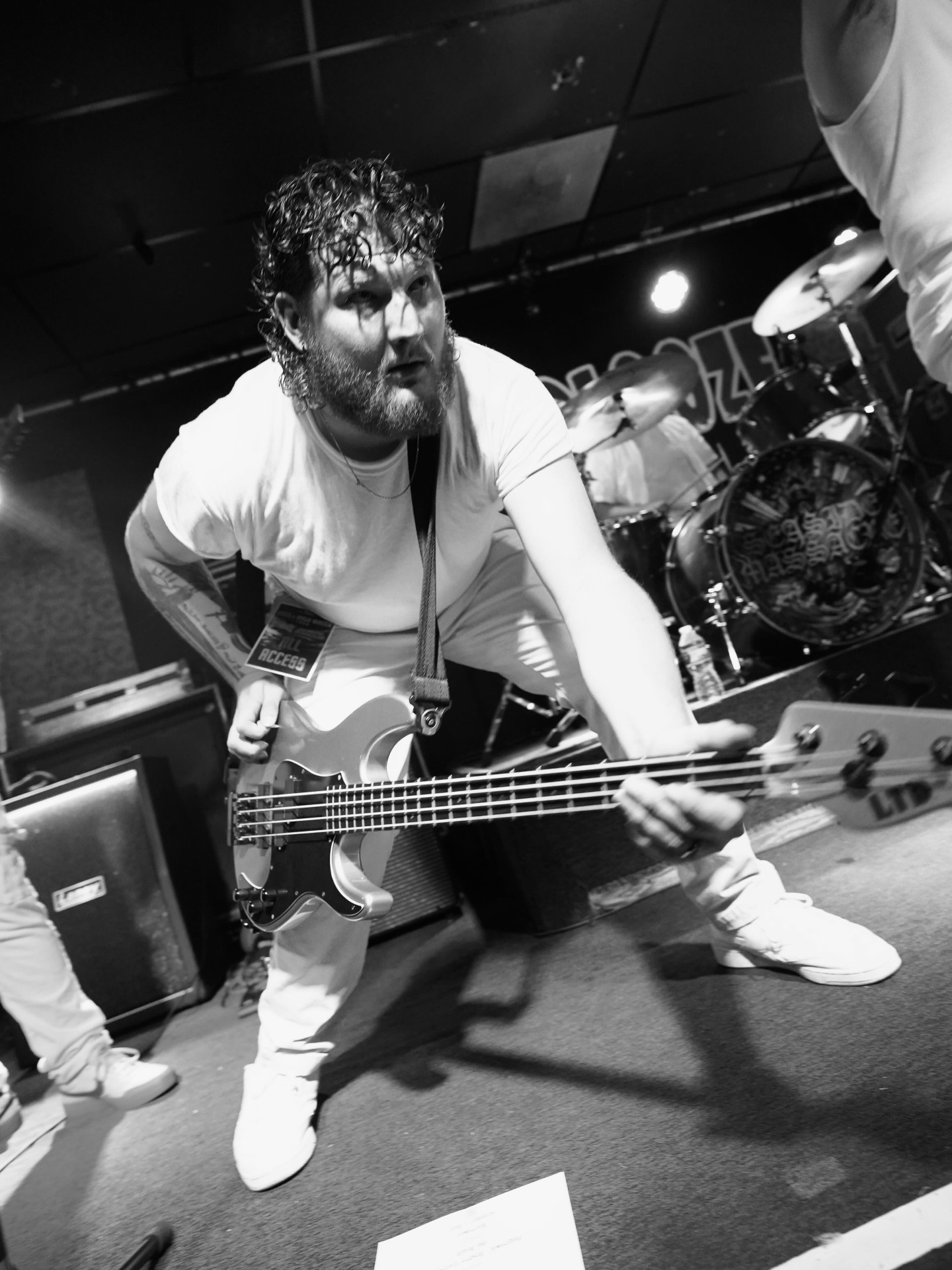 Bassist leaning forward on stage in black and white