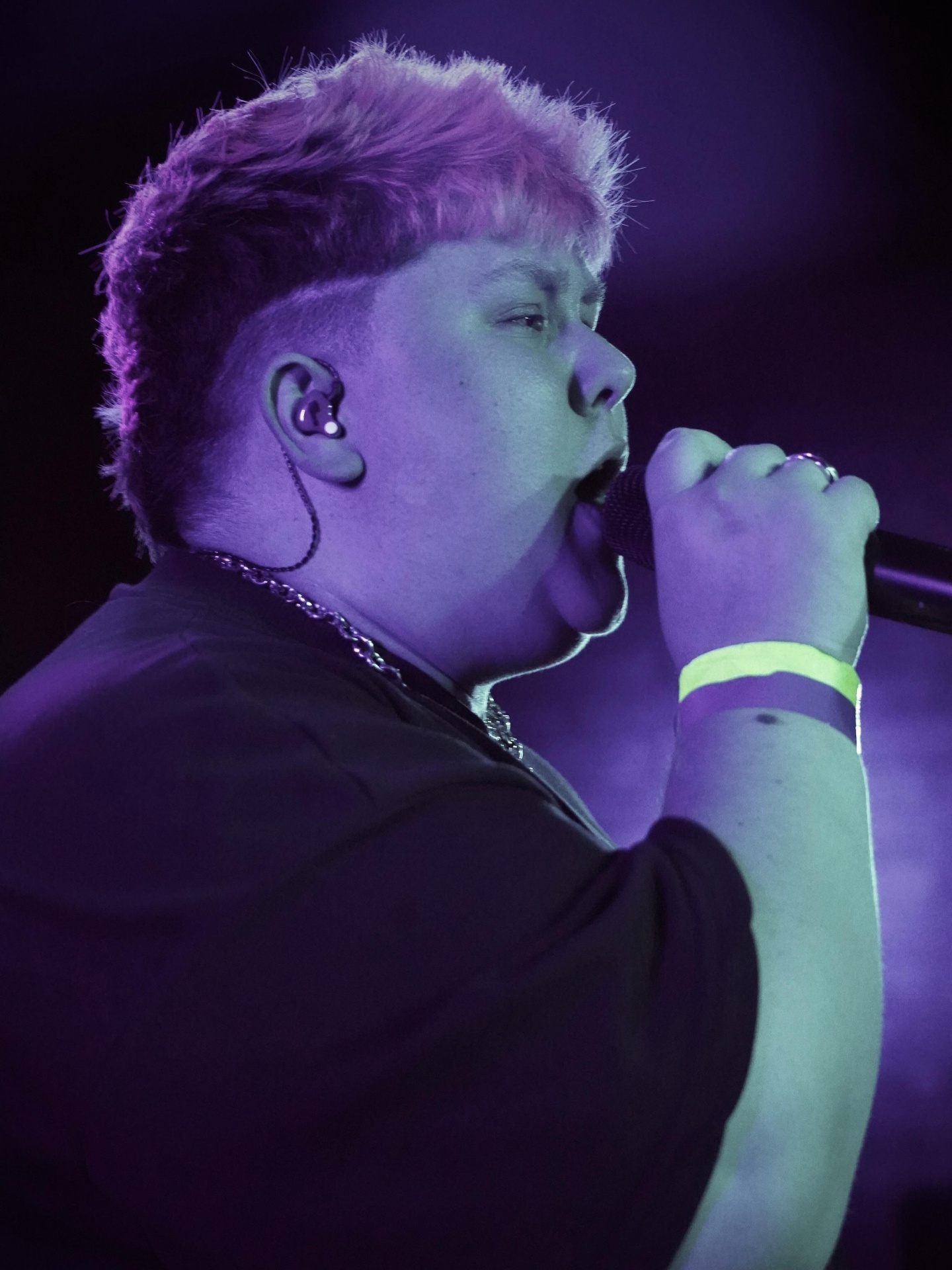 Vocalist with pink hair singing under purple light
